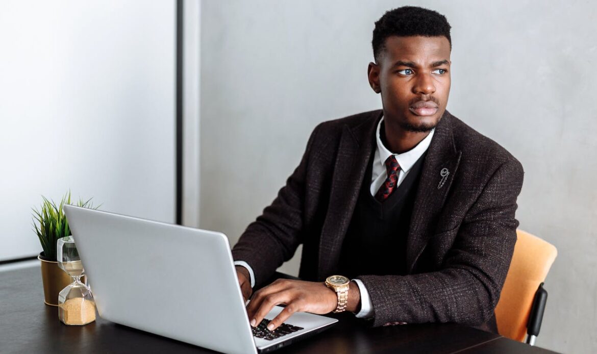Confident businessman working on laptop at desk, focusing on tasks.