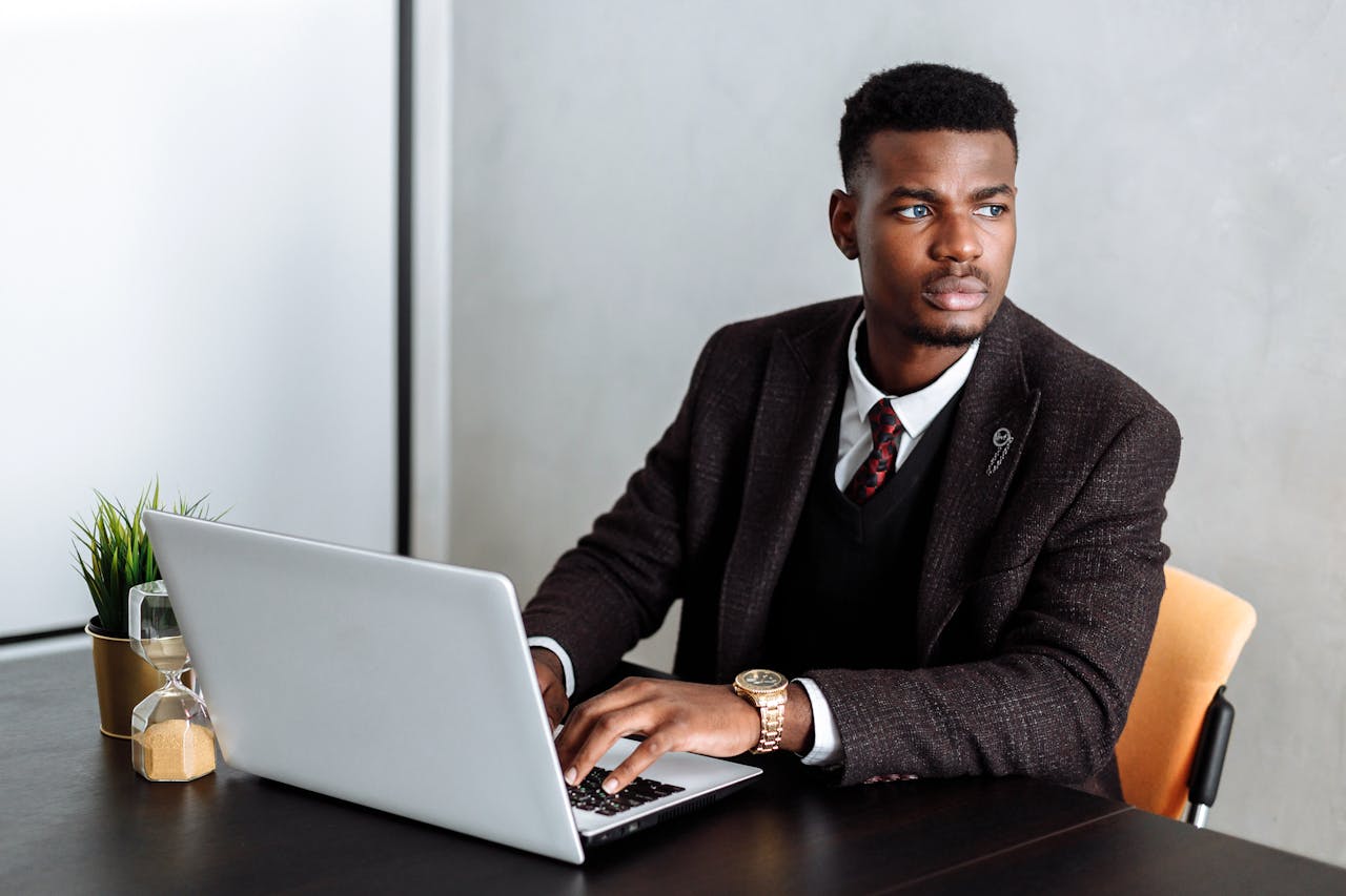 Confident businessman working on laptop at desk, focusing on tasks.