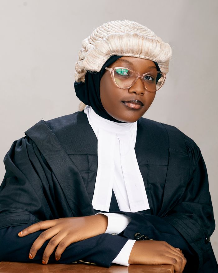 About US Portrait of a confident female lawyer wearing a wig and gown in a studio setting in Kano, Nigeria.