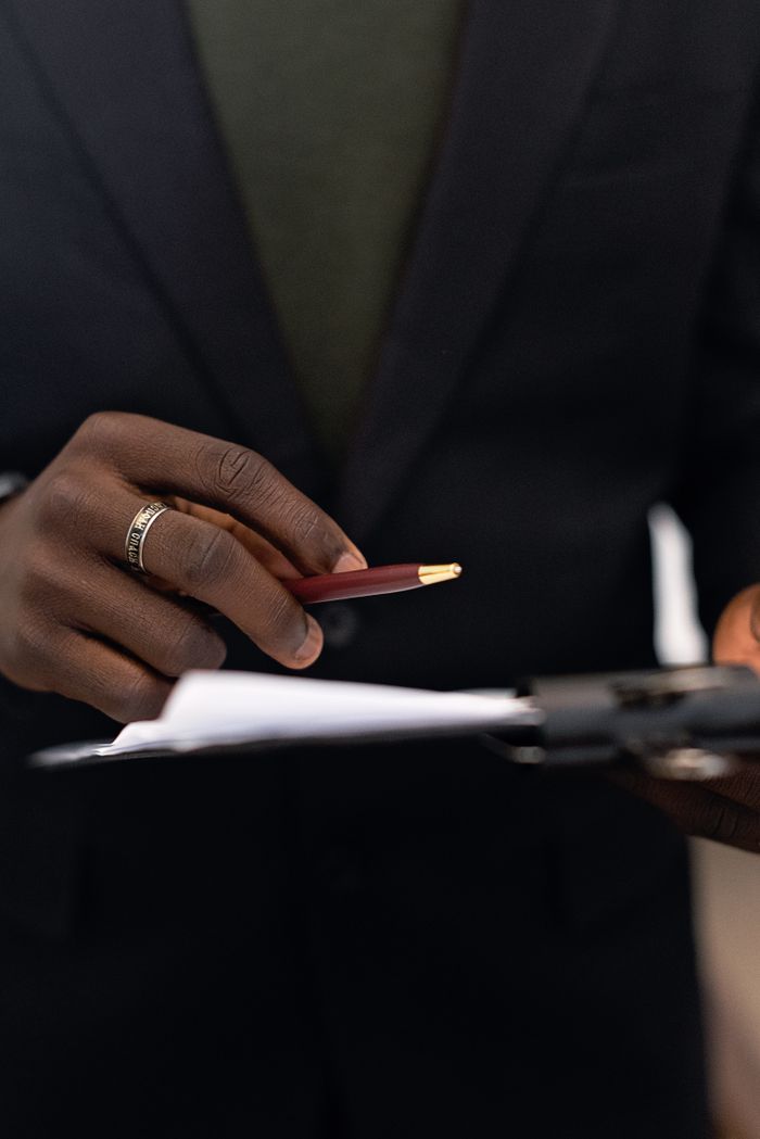 Services Close-up of a business professional holding a pen and reviewing documents on a clipboard.
